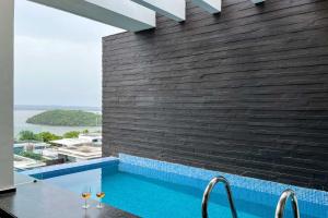 uma piscina com dois copos de vinho ao lado de uma parede de tijolos em StayVista at Tarika's Seascapes with Pool & Home Theatre em Dabolim