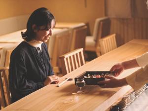 a woman sitting at a table with a plate of food at SOKI Kanazawa in Kanazawa