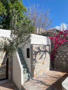 une maison blanche avec un escalier et des fleurs roses dans l'établissement Èlia Luxury Rooms, à Areópoli