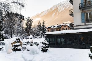 un cortile coperto da neve con un edificio e una montagna di Hôtel Mont-Blanc Chamonix a Chamonix-Mont-Blanc