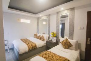 a hotel room with two beds and a mirror at Hotel Carmelita in Tuguegarao City