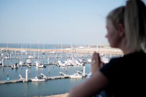 Una donna che guarda fuori da una finestra al porto di Leonardo Hotel IJmuiden Seaport Beach a IJmuiden