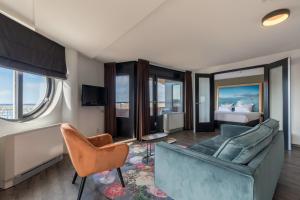 un soggiorno con divano, sedie e letto di Leonardo Hotel IJmuiden Seaport Beach a IJmuiden