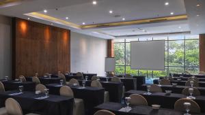 una sala conferenze con tavoli, sedie e schermo di Veranda Hotel Pakubuwono a Giacarta