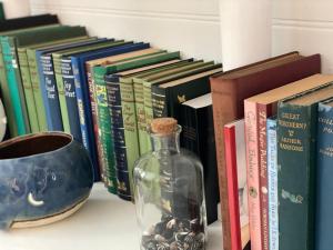 une bouteille de verre assise à côté des livres sur une étagère dans l'établissement Cosy coastal cottage- Allwood Harbour, à Kiama