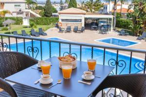 - une table avec deux verres de jus d'orange et un bol de fruits dans l'établissement Atalaia Sol Aparthotel - tennis & heated pool in winter, à Lagos