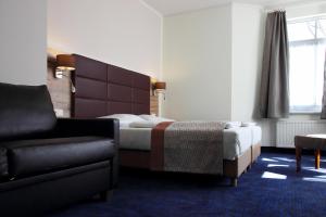 um quarto de hotel com uma cama e uma cadeira em Rathaushotels Oberwiesenthal All Inclusive em Kurort Oberwiesenthal