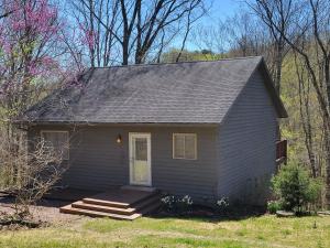 une petite maison grise avec une véranda et une porte dans l'établissement Preston Hollow, à Bloomington