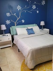 - une chambre avec un lit et un mur bleu orné de fleurs blanches dans l'établissement Preston Hollow, à Bloomington