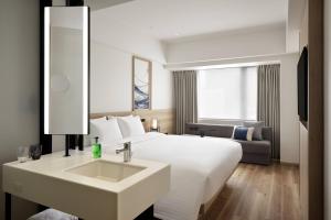 Fairfield by Marriott Osaka Namba في أوساكا: غرفة فندق بسرير ابيض ومغسلة