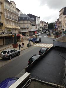 una strada cittadina con auto parcheggiate in un parcheggio di Hôtel Le Milan a Lourdes