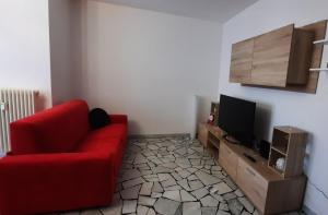 een woonkamer met een rode bank en een tv bij Verdisuite - Trento centro - Parcheggio privato gratuito in Trento