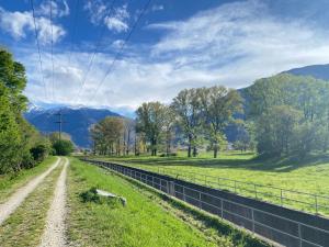 un camino de tierra en un campo con montañas en el fondo en Soggiorna nel Cuore del Ticino, en Giubiasco