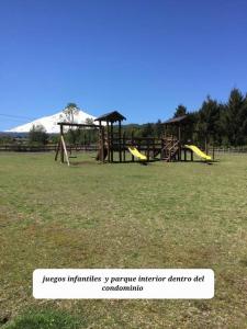 um parque com escorregas e um parque infantil com uma montanha em Agradable Cabaña inserta en bosque nativo em Pucón