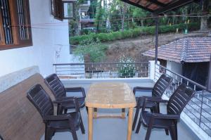 un tavolo e sedie su un balcone con tavolo di Misty Retreat (Pragati House) a Madikeri