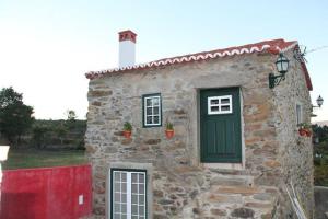 een stenen huis met een groene deur en een rood hek bij Casa Do Salgueiral in Fundão