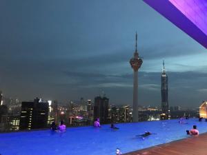 un grupo de personas sentadas en el borde de un edificio en The Platinum KLCC By Sky Pool, en Kuala Lumpur