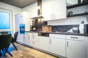 a kitchen with white cabinets and a sink and a table at Ferienwohnung Residenz Bollwark in Kappeln