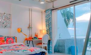 Schlafzimmer mit einem Bett, einem Schreibtisch und einem Fenster in der Unterkunft มารินอส บีชเฮ้าส์ Marinos Beach house in Si Racha