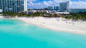 Magnifica Villa Palmeras Pok ta Pok Zona Hotelera Cancun في كانكون: اطلالة جوية على شاطئ فيه ناس في الماء