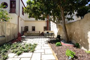 une terrasse avec un arbre, une table et des chaises dans l'établissement Entre Ruas Apartments, à Coimbra