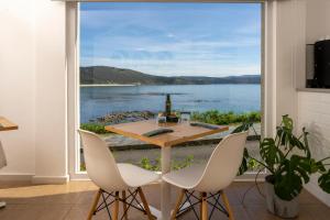 een tafel en stoelen met uitzicht op het water bij Hotel Mar de Fisterra in Finisterre