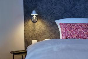 a bed with a red pillow and a lamp on a wall at à la pointe de l'ile in Namur