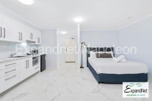 a white bedroom with a bed and a kitchen at Napoleon On Kent in Sydney