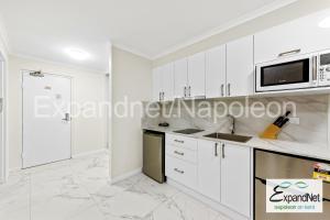 a kitchen with white cabinets and a microwave at Napoleon On Kent in Sydney