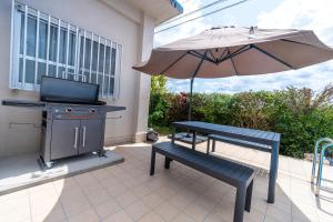 eine Terrasse mit einem Grill, einer Bank und einem Sonnenschirm in der Unterkunft private house noko in Miyako-jima