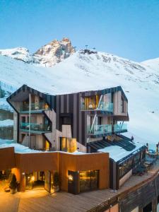 um edifício com uma montanha coberta de neve ao fundo em Bergman Mountain Hotel em Breuil-Cervinia