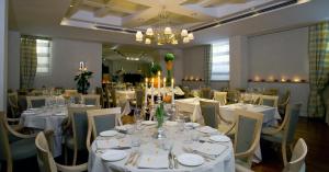 a dining room with white tables and chairs and a chandelier at Hotel Clitunno in Spoleto