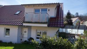 una casa bianca con un balcone sopra di Appartement Tischi a Ilsenburg