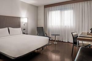 um quarto de hotel com uma grande cama branca e uma secretária em AC Hotel Porto by Marriott no Porto