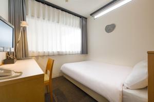 1 dormitorio con cama, escritorio y ventana en Hotel Oak Shizuoka, en Shizuoka