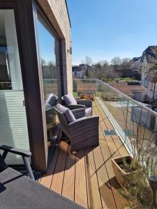 a wooden deck with two chairs on a balcony at Moderne Penthouse Wohnung in Schleswig