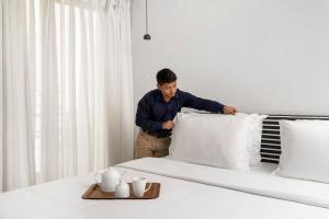 a man is putting pillows on a bed at Bungalow 157 in New Delhi