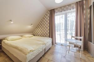 a bedroom with a bed and a table and a window at Villa Arkadia in Łukęcin