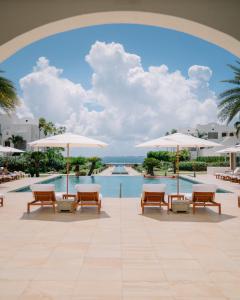 - une piscine dans un complexe avec des chaises et des parasols dans l'établissement Aurora Anguilla Resort & Golf Club, à Rendezvous Beach