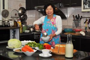 Una donna in piedi in una cucina che prepara il cibo di Yunju House a Jiaoxi