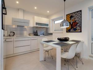 a white kitchen with a table and white chairs at Traumkoje im Herzen Westerlands strandnah Meer in Westerland (Sylt)