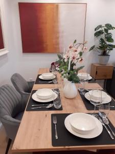 NEW - Apartment Kameni Confort Wifi Munich Airport Family في نيوفهارن بي فريسنج: طاولة خشبية عليها صحون و فضيات