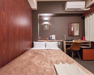 a bed in a room with a desk and a bed sidx sidx sidx at HOTEL RELIEF Kokura Station in Kitakyushu