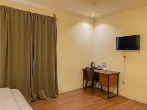 um quarto com uma secretária, uma cama e uma televisão em Urbanview Hotel ME Jayapura em Jayapura