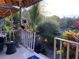 uma mulher de pé numa varanda a olhar para uma palmeira em The Pancor Jungle Resort em Nusa Penida