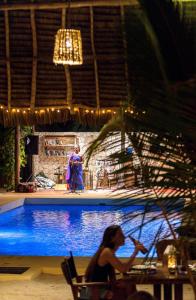 eine Frau auf einem Stuhl neben einem Pool in der Unterkunft Zanzibar Sunrise at Bandas in Matemwe