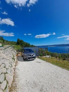 une voiture garée sur une route en gravier à côté de l'eau dans l'établissement Bella vista with jacuzzi 1, à Omiš