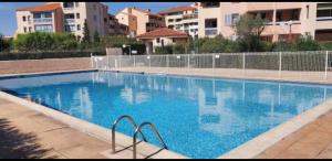 una gran piscina azul con edificios en el fondo en Appartement Design, en Fréjus