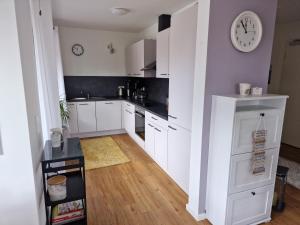 a kitchen with white cabinets and a clock on the wall at Moderne Penthouse Wohnung in Schleswig