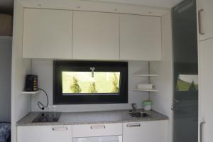 にあるTiny House in ruhiger Lageの白いキャビネットと壁掛けテレビ付きのキッチン